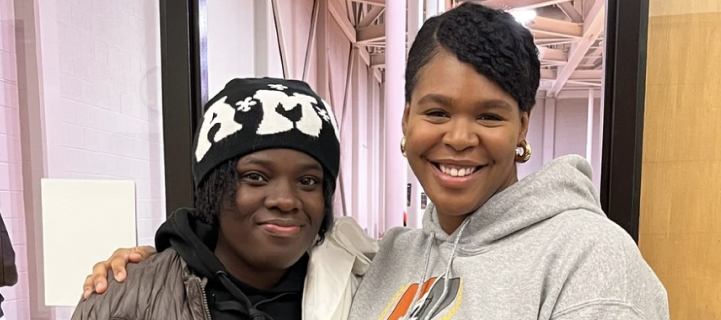 A student and Success navigator Shawnte side hugging and smiling at the camera
